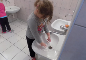 Nadia ćwiczy prawidłowe mycie rąk przy umywalce.